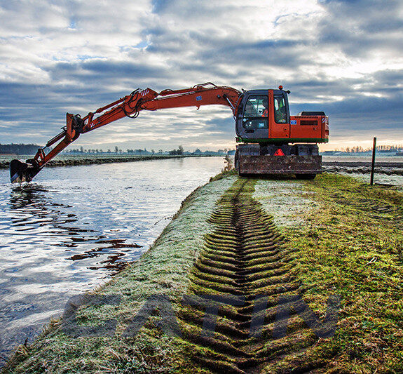 Dredging of an inland canal by cranes in winter at sunset.